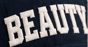Close-up of raised white BEAUTY embroidery on navy