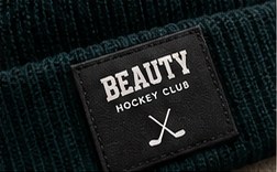 Woven BEAUTY Hockey Club label on a forest beanie